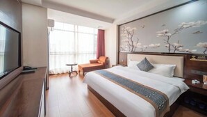Una camera d'albergo con un letto grande, una televisione, un tavolino, una sedia e una finestra con tende.