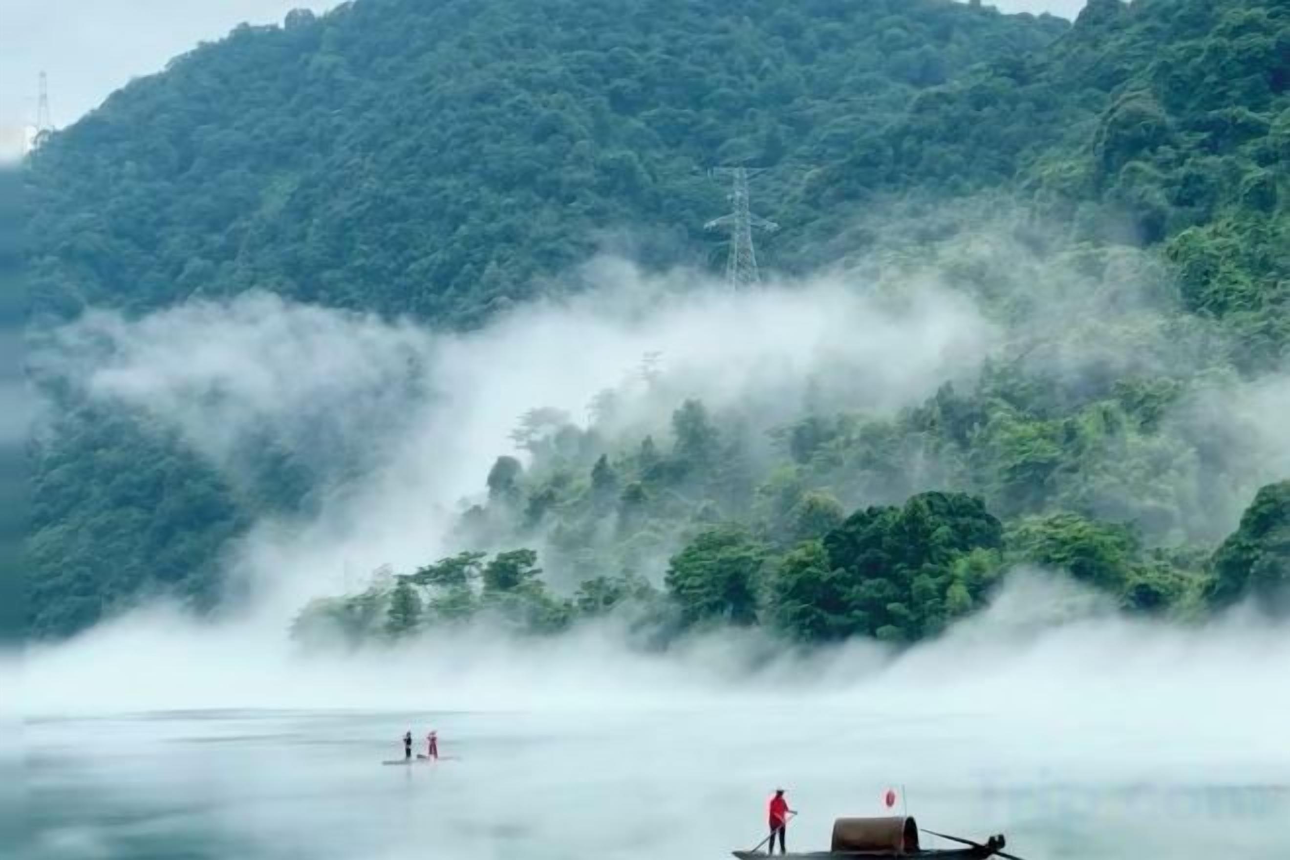 A misty lake with a boat and a person standing on a dock.