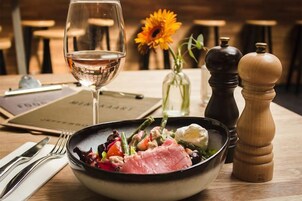 Una mesa de comedor con un plato de comida, una copa de vino y un menú.