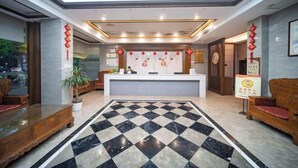 Una hall d'albergo con pavimento a scacchi, una reception e arredamento tradizionale.