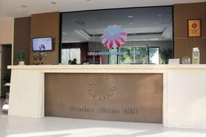 Un mostrador de recepción con un logotipo, una pantalla de televisión y un certificado enmarcado en la pared.