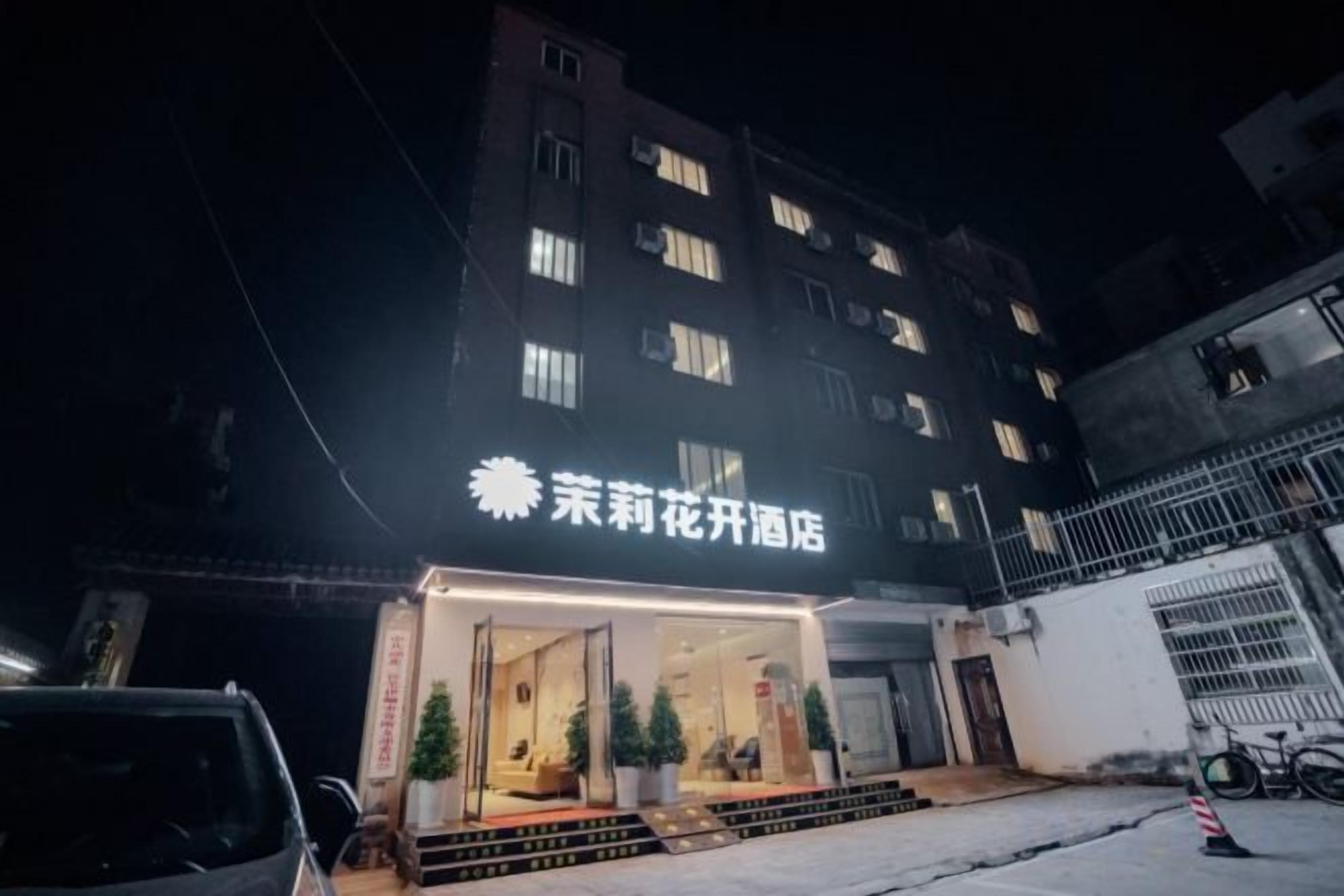 A hotel with a sign indicating it is a flower hotel. There are steps leading to the entrance, and a few potted plants are visible outside.
