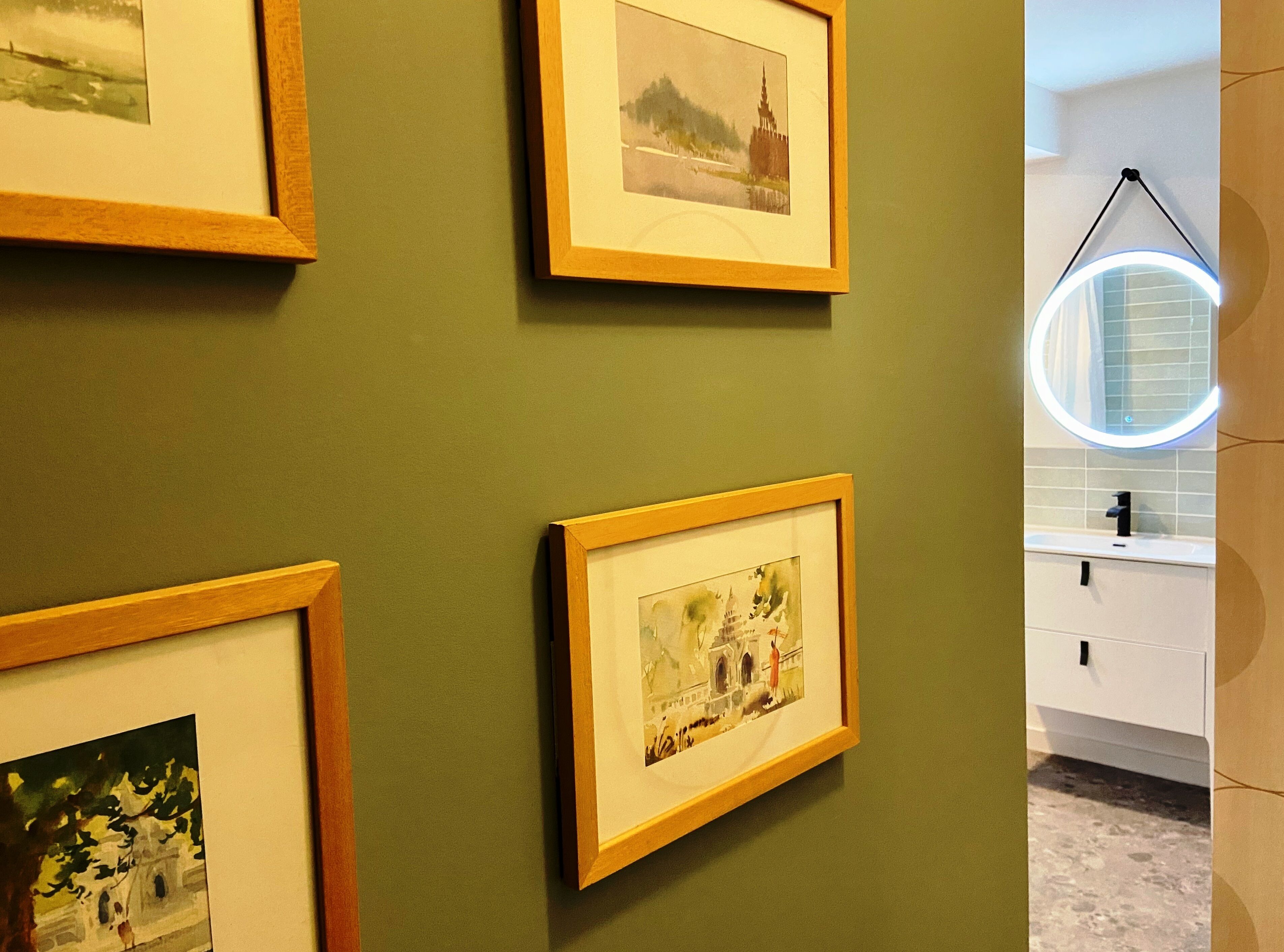 Una pared con múltiples obras de arte enmarcadas.