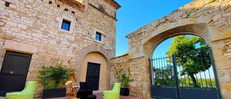 A stone building with an arched entrance, outdoor seating, and a decorative sculpture.