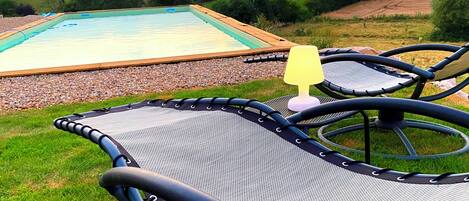 Uma área de piscina com trampolim e espreguiçadeiras.
