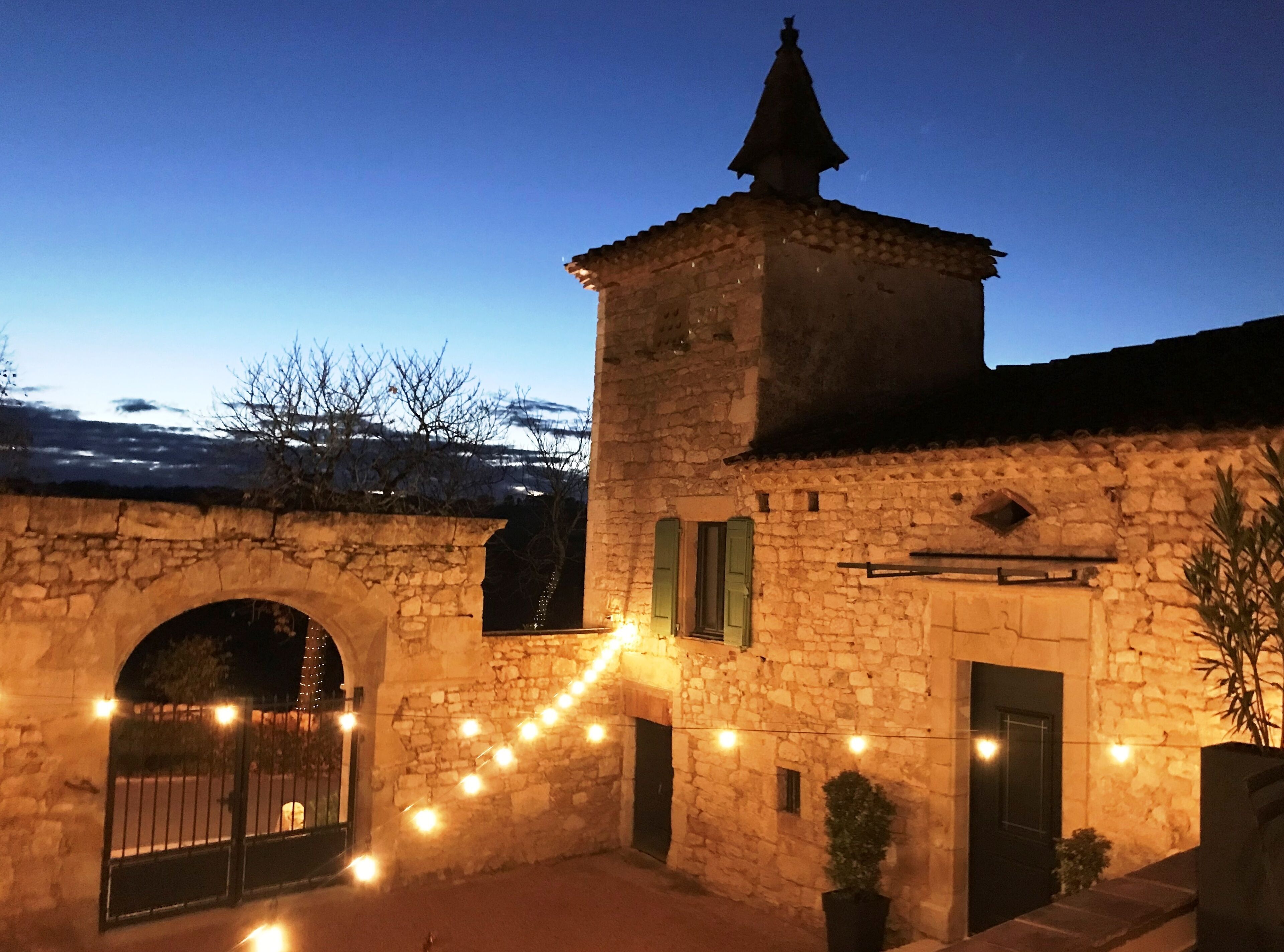 A stone building with a tower, arched entrance, and string lights.