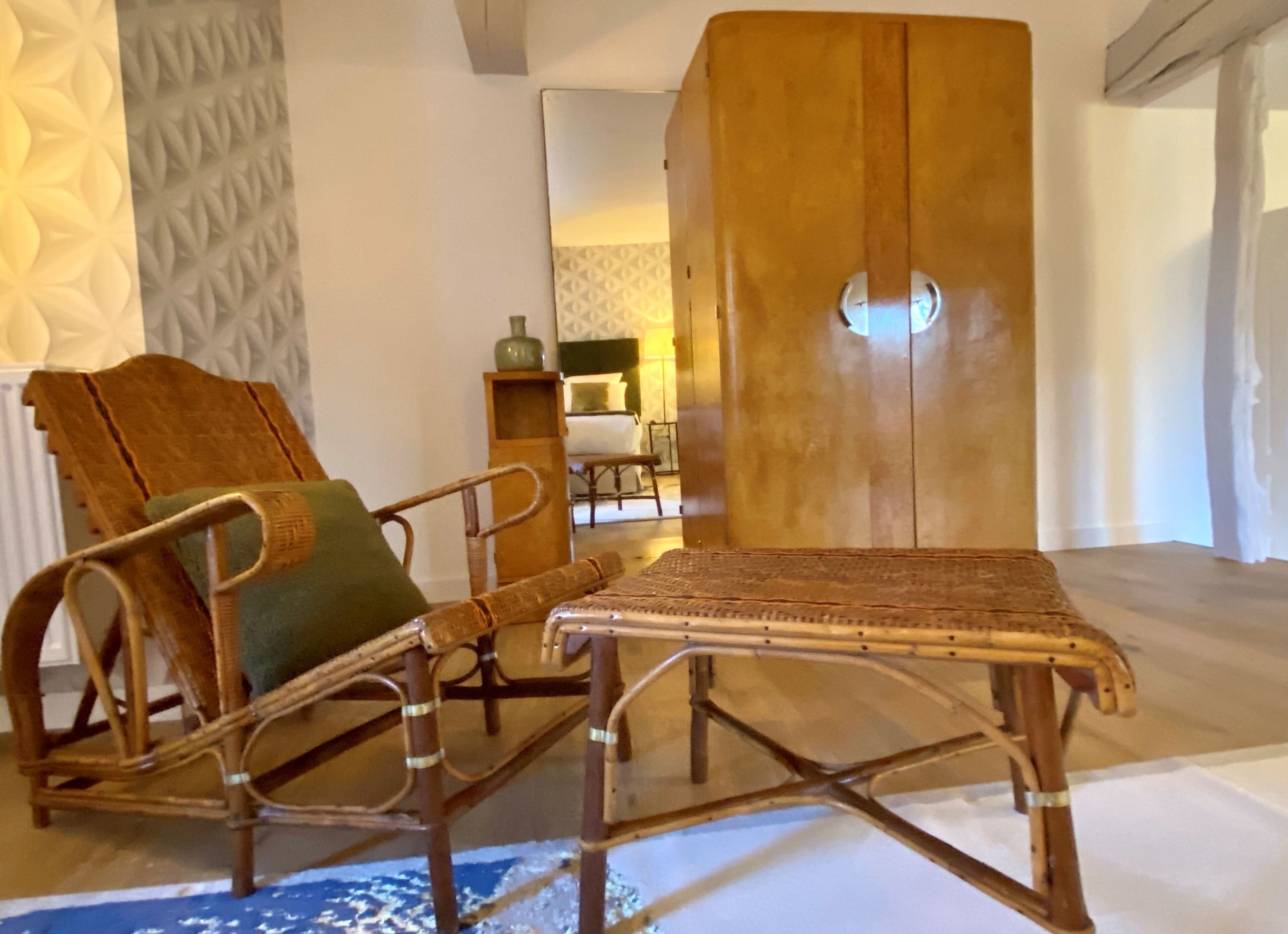 Une pièce comprenant une chaise en osier, une petite table et une armoire en bois.