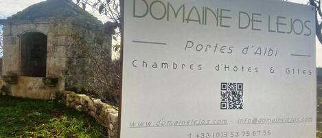 A sign for Domaine de Lejos, listing rooms and sites, with a QR code and contact information.