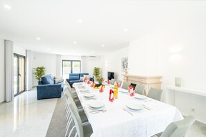 Un comedor moderno con una mesa larga dispuesta para una comida, rodeado de asientos cómodos y una chimenea.