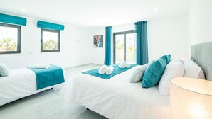 Une chambre d’hôtel avec deux lits, une grande fenêtre et une vue sur des palmiers.