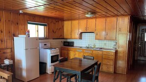 A wooden-paneled kitchen with a refrigerator, stove, microwave, and wooden cabinets. - Gresham Shores - Hungry Bear - PET FRIENDLY (Arbor Vitae)
