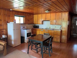 Eine Küche mit Holzwandverkleidung, ausgestattet mit einem Kühlschrank, Herd, Mikrowelle und Holzschränken.