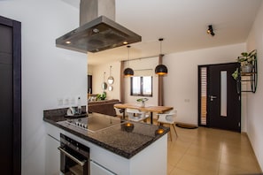 A modern kitchen with a central island, built-in oven, and pendant lighting.