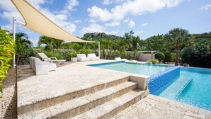 A swimming pool with steps leading into it, surrounded by lounge chairs and a shaded area. - Blue Bay Green View (Sint Michiel)