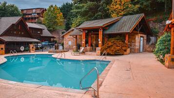 A pool area with a clear view of the pool, lounge chairs, and a building with a stone facade.