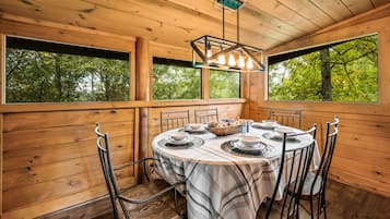 A wooden interior with a round table set for dining, surrounded by metal chairs.