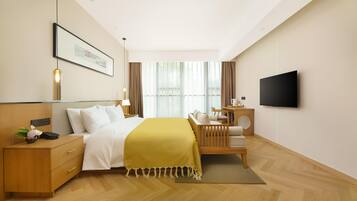 A modern hotel room with a bed, bedside table, lamp, and a flat-screen TV.