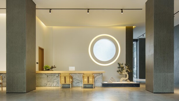 A modern reception area with a marble counter, two wooden chairs, a round illuminated mirror, and a potted plant. - Blossom Hill Hotel Ya'an Mengdingshan (Ya'an)
