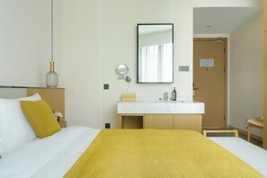 A hotel room with a bed, a bedside table with a lamp, a mirror, a wooden door, and a bathroom with a sink and mirror. - Blossom Hill Hotel Ya'an Mengdingshan (Ya'an)