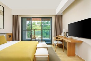 A hotel room with a bed, a desk, a flat-screen TV, and a sliding glass door leading to an outdoor area. - Blossom Hill Hotel Ya'an Mengdingshan (Ya'an)
