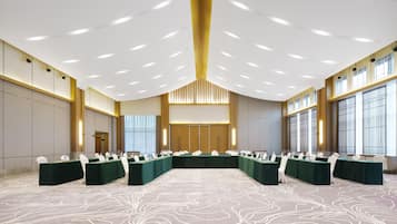 Un amplio salón de conferencias con una larga mesa, numerosas sillas y una alfombra estampada.