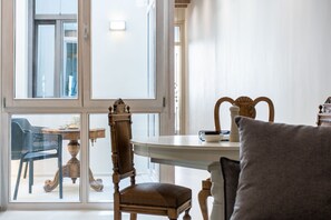 Una habitación con un ventanal grande, una silla de madera, una mesa y un sofá.
