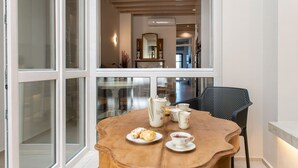 A dining area with a table set for tea, a chair, and a view through large windows. - Modernly furnished family suite with sea view, just in front of the Palm beach (Rethymno)