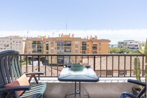 A balcony with a table and chairs, overlooking a residential area with buildings and a clear sky. - "Rincón Candelaria" Apartment (Rincón de la Victoria)