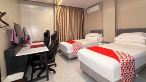 A hotel room with a desk, two beds, a chair, and a curtain.