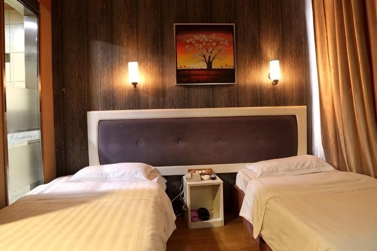 Une chambre d’hôtel avec deux lits, une tête de lit, une table de chevet et un tableau au mur.