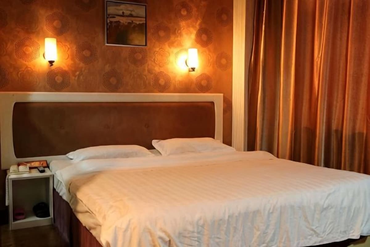 Une chambre d’hôtel avec un grand lit, deux lampes de chevet, une table de chevet et une tête de lit.