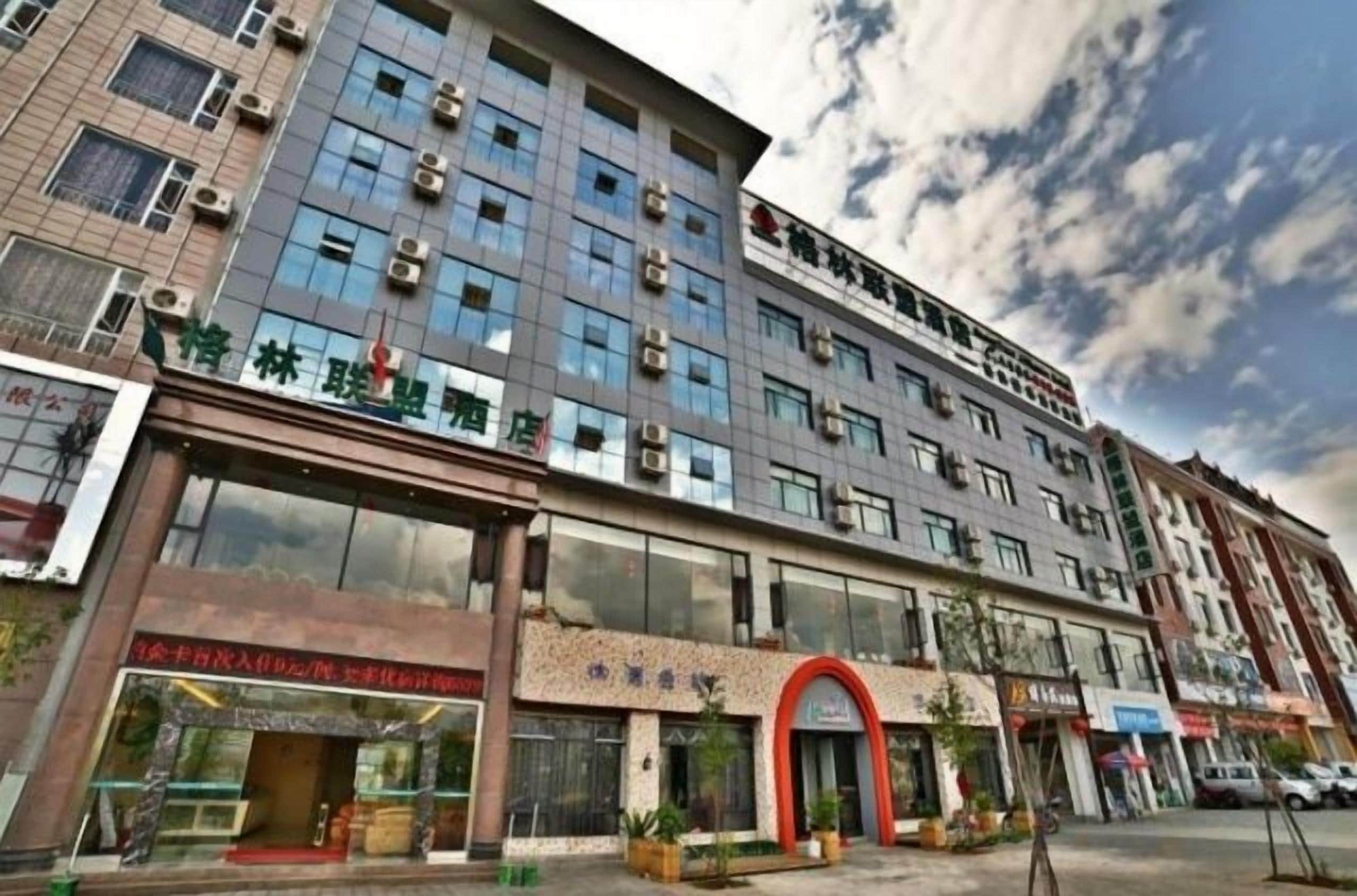 Ein mehrstöckiges Hotel mit moderner Fassade, großen Fenstern und einem gut sichtbaren Eingang mit rotem Bogen.