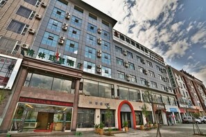 A multi-story hotel with a modern facade, large windows, and a red archway entrance. - Green Alliance (Dali Yongpingbo South Road Shop) (Yongping)