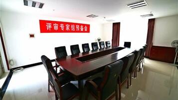 Une salle de conférence avec une longue table, des chaises et un panneau rouge accroché au mur.