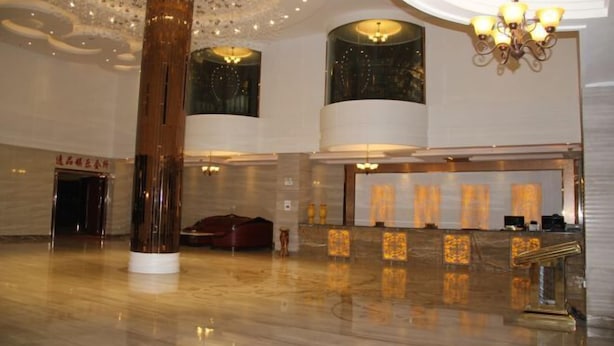 Un lobby amplio con techo alto, una columna central y un mostrador de recepción.
