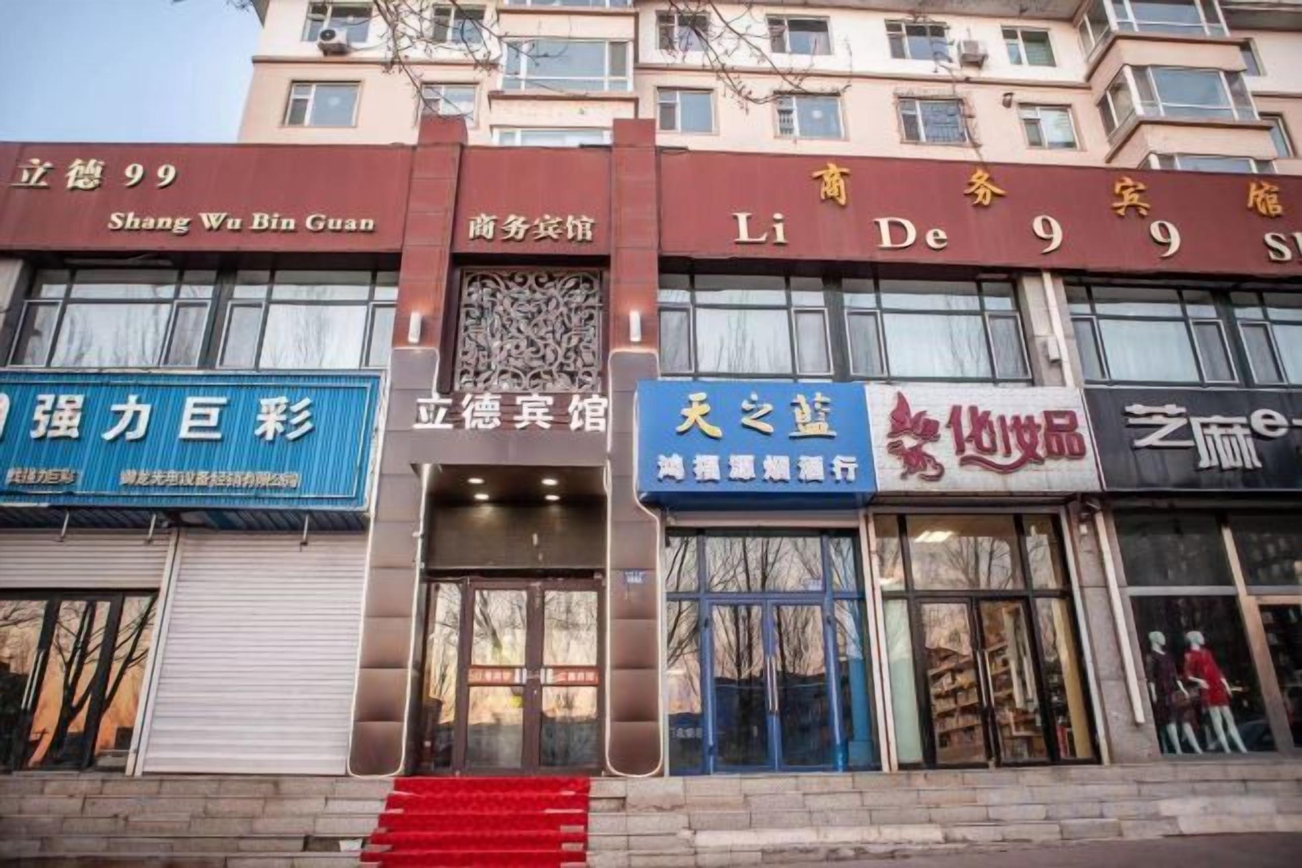A building with multiple storefronts, including a visible entrance with a red staircase leading up to the door.