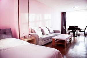 A hotel room with a bed, a sofa, a small table, and a dining area with chairs.