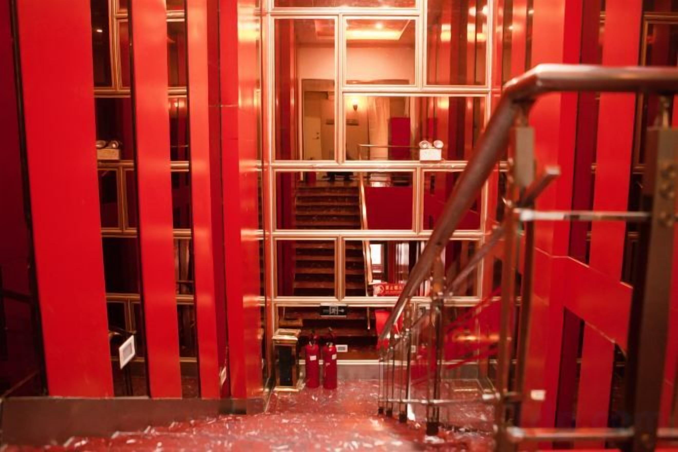 A corridor with red walls and a metal railing.