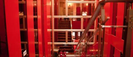 A corridor with red walls and a metal railing.