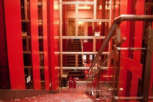 A corridor with red walls and a metal railing.