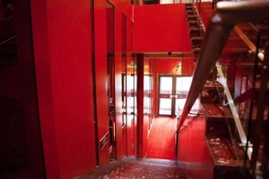 Un pasillo rojo con una escalera que sube a un nivel superior.
