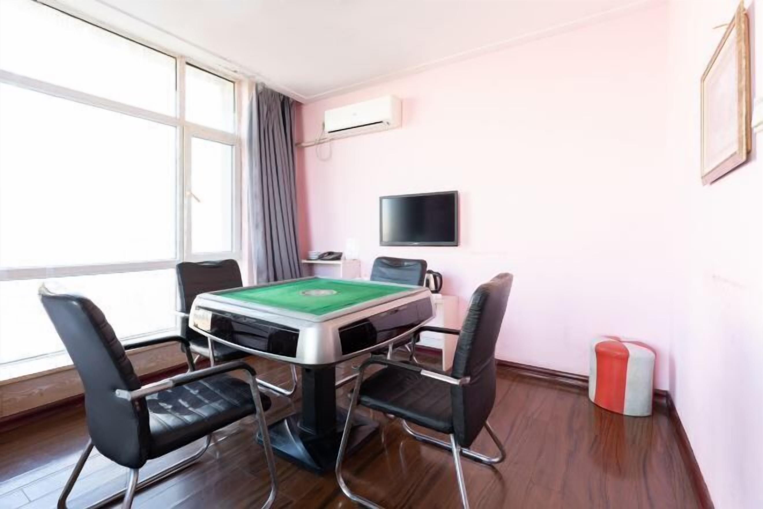 A room with a pool table, four chairs, a television, and an air conditioning unit.