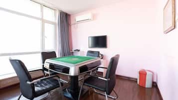 A room with a pool table, four chairs, a television, and an air conditioning unit.