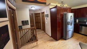 A kitchen with wooden cabinets, a stainless steel refrigerator, and a wooden staircase leading to another room. - Deadwood & Sturgis 5 bedroom next to golf course (Sturgis)