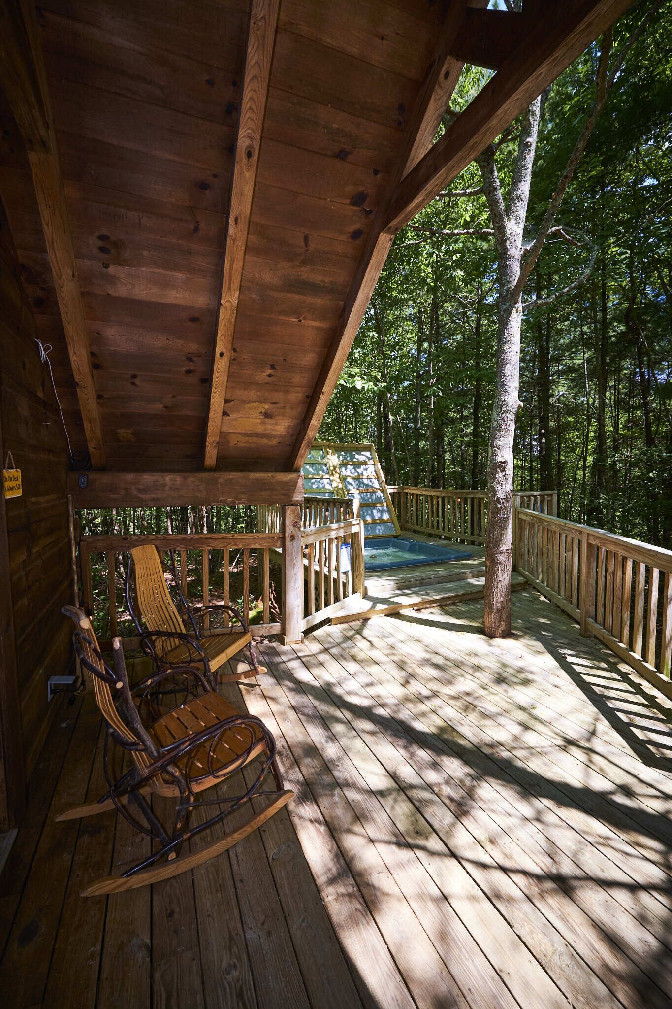 Une terrasse en bois avec une chaise suspendue en bois et une petite piscine.
