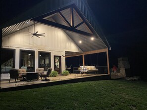 Ein modernes Haus mit überdachter Terrasse, großen Fenstern und einem Schaukelstuhl.