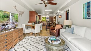Ein modernes Wohnzimmer mit einem weißen Sofa, einem Holztisch und einem Essbereich mit Tisch und Stühlen.