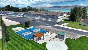 A hotel with a tennis court, a covered seating area, and a parking lot. - The Sandbar #41 - Lake, Pool and Hot Tub Access! (Garden City)
