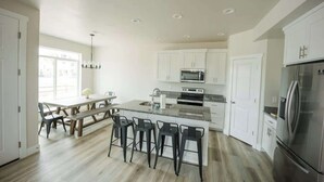 A modern kitchen with white cabinets, a stainless steel refrigerator, a built-in oven, and a granite countertop. - The Sandbar #41 - Lake, Pool and Hot Tub Access! (Garden City)