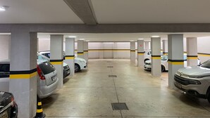 A multi-level parking garage with concrete pillars, yellow and black striped lines, and several parked cars. - HOTEL SEVEN (Goiânia)